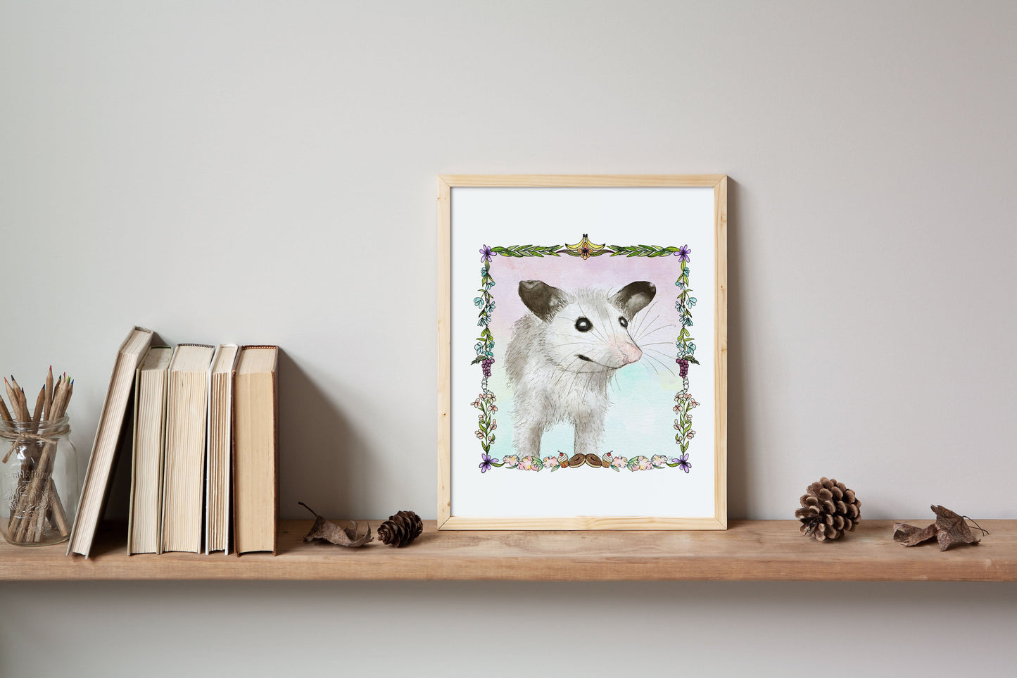 An Opossum portrait sits on a wooden shelf with books, pencils in a jar, and some ephemera from nature